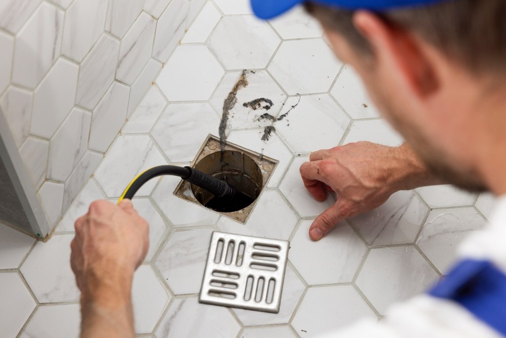 Plumber clearing a blocked drain line